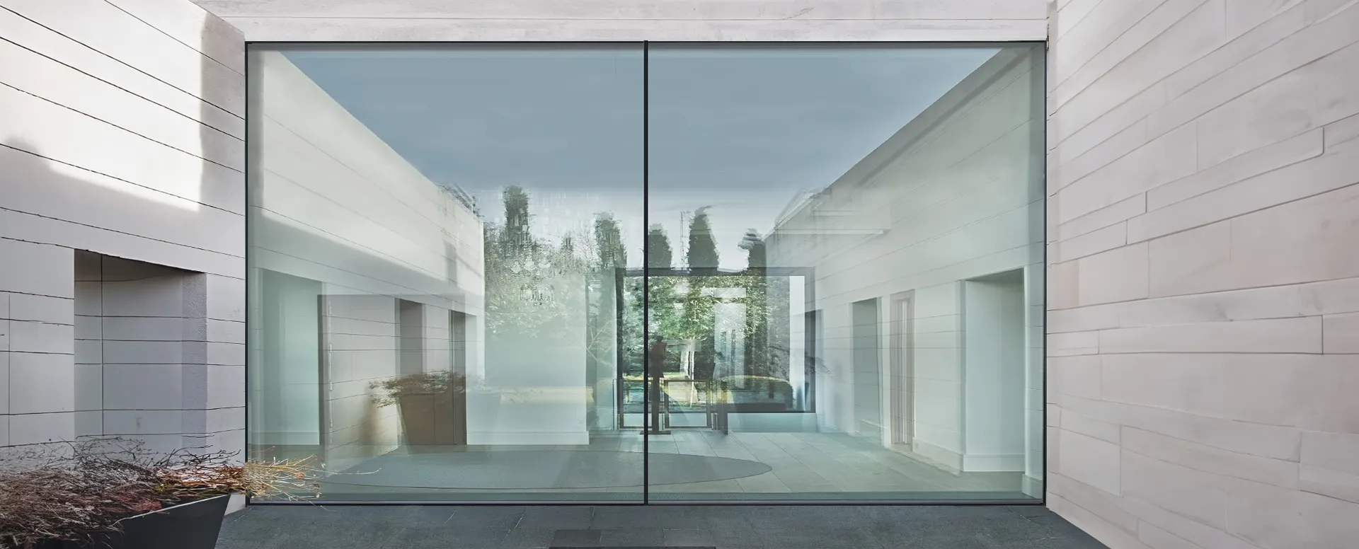 Cortizo COR Vision Plus sliding door with a slim central junction in a modern stone facade