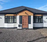 Wood-effect aluminium front door between anthracite bay windows on a bungalow