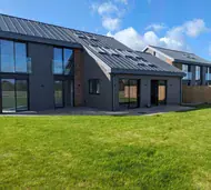 Rear of a new-build home with dark grey aluminium windows and full-height glazing