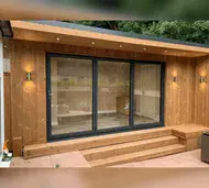 Anthracite three-panel bifold doors in a timber-clad garden room