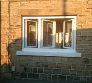 White uPVC casement window with three sashes opened outwards in a stone wall