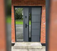 Grey steel front door with a vertical glass strip and a full-height glazed side panel
