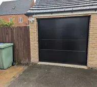 Black sectional garage door on a brick garage