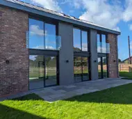 Frameless glass Juliet balconies across upper-floor full-height aluminium glazing