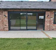 Anthracite aluminium lift and slide doors in a red-brick barn conversion