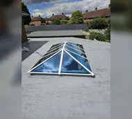 Glass roof lantern with a white frame on a flat roof extension