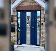 Navy steel front door with a vertical glass strip and two glazed side panels on a brick house