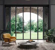 Floor-to-ceiling black steel glazed doors opening onto a garden