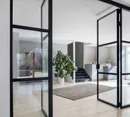 Black steel internal glazed screen with an open door in a bright hallway