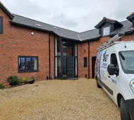 Anthracite grey uPVC tilt and turn windows on a red-brick new-build home, with a Windows4You van on the drive